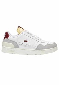 Sneakers Lacoste in pelle bianca con dettagli in suede grigio. Presentano particolari perforati, lacci bianchi, una linguetta rossa sul tallone e una suola strutturata.