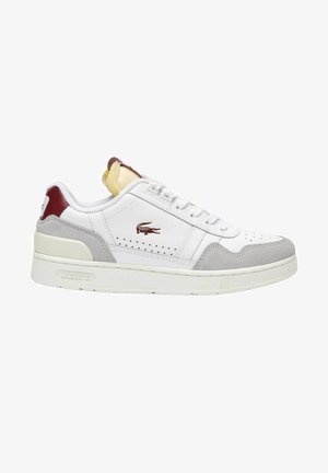 Sneakers Lacoste z białej skóry z szarymi zamszowymi akcentami. Posiada perforowane detale, białe sznurówki, czerwony język na pięcie oraz teksturowaną podeszwę.