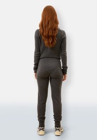 Szary dres o slim fit, z długimi rękawami i elastycznym pasem, zestawiony z masywnymi sneakersami, widok z tyłu.