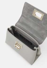 Lys grå læder clutch med guldtonet lås, åben klap og indvendig lynlåslomme mærket Furla.