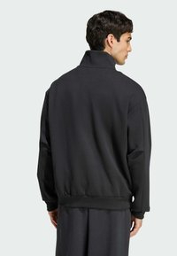 Čierny sveter s vysokým golierom, voľný strih, rebrované manžety a lem. Vyrobený z jemného materiálu s hladkou textúrou a minimalistickým dizajnom.