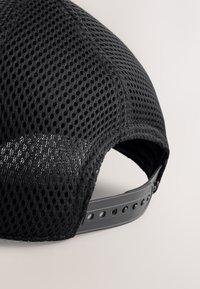 Cappellino nero in mesh con superficie testurizzata, forma arrotondata e cinturino regolabile in plastica sul retro con fori multipli per la regolazione della taglia.