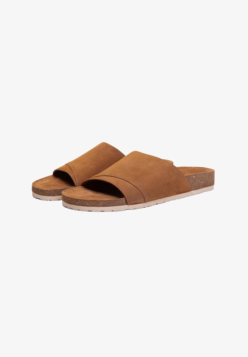 Paire de sandales slides en suède marron à bout ouvert avec larges brides et semelles rembourrées de couleur claire sur fond blanc.