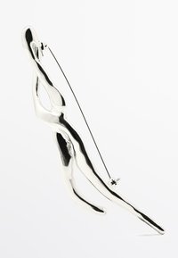 Zilveren metalen broche met een vloeiende menselijke figuurontwerp, voorzien van een gladde, reflecterende oppervlakte en een speldsluiting voor bevestiging.