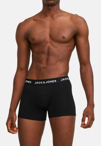 Schwarze Baumwollboxershorts mit einem weißen, markierten Bund mit dem Text "JACK & JONES". Das Design ist eng anliegend und hat eine glatte Textur.