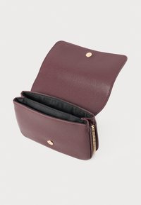 Portafoglio in pelle bordeaux con finitura testurizzata, hardware dorato, chiusura con zip e due scomparti interni foderati in tessuto nero.