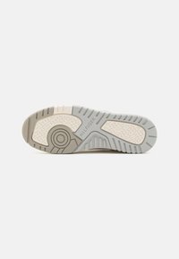 Suola di sneaker beige con modelli di trazione in gomma grigia testurizzata, accenti circolari e logo "HILFIGER" impresso sul lato.