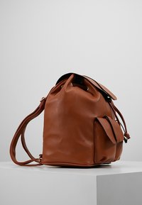 Braune Leder-Eimer-Tasche mit texturierten Oberflächen, Zugverschluss und einer Seitentasche. Verfügt über einen abnehmbaren Schultergurt.