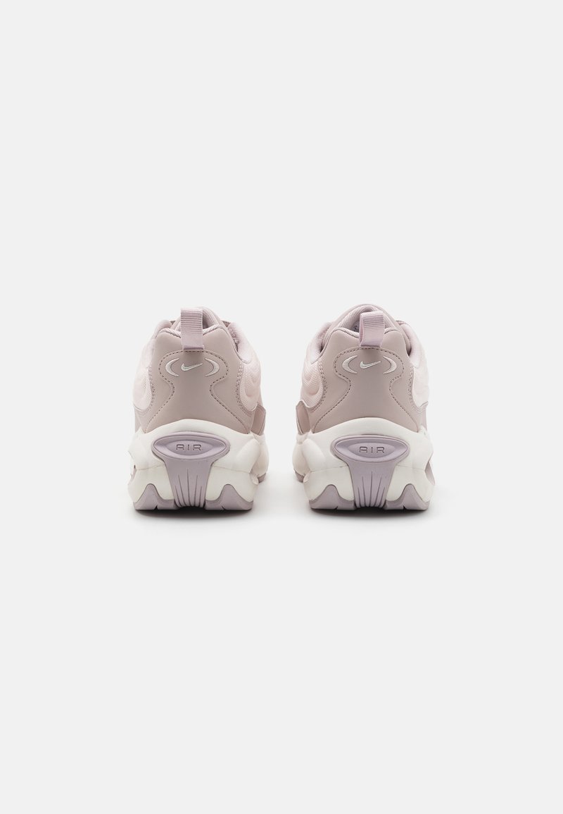 Zapatillas moradas y blancas con diseño texturizado, suelas pronunciadas y tiradores traseros. Presentan un logotipo circular y amortiguación de aire visible.
