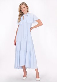 Kleid светло-блакитного кольору з м'якої тканини з багатоярусним подолом, з коміром та легкими рукавами. В парі з білими туфлями на високих підборах.
