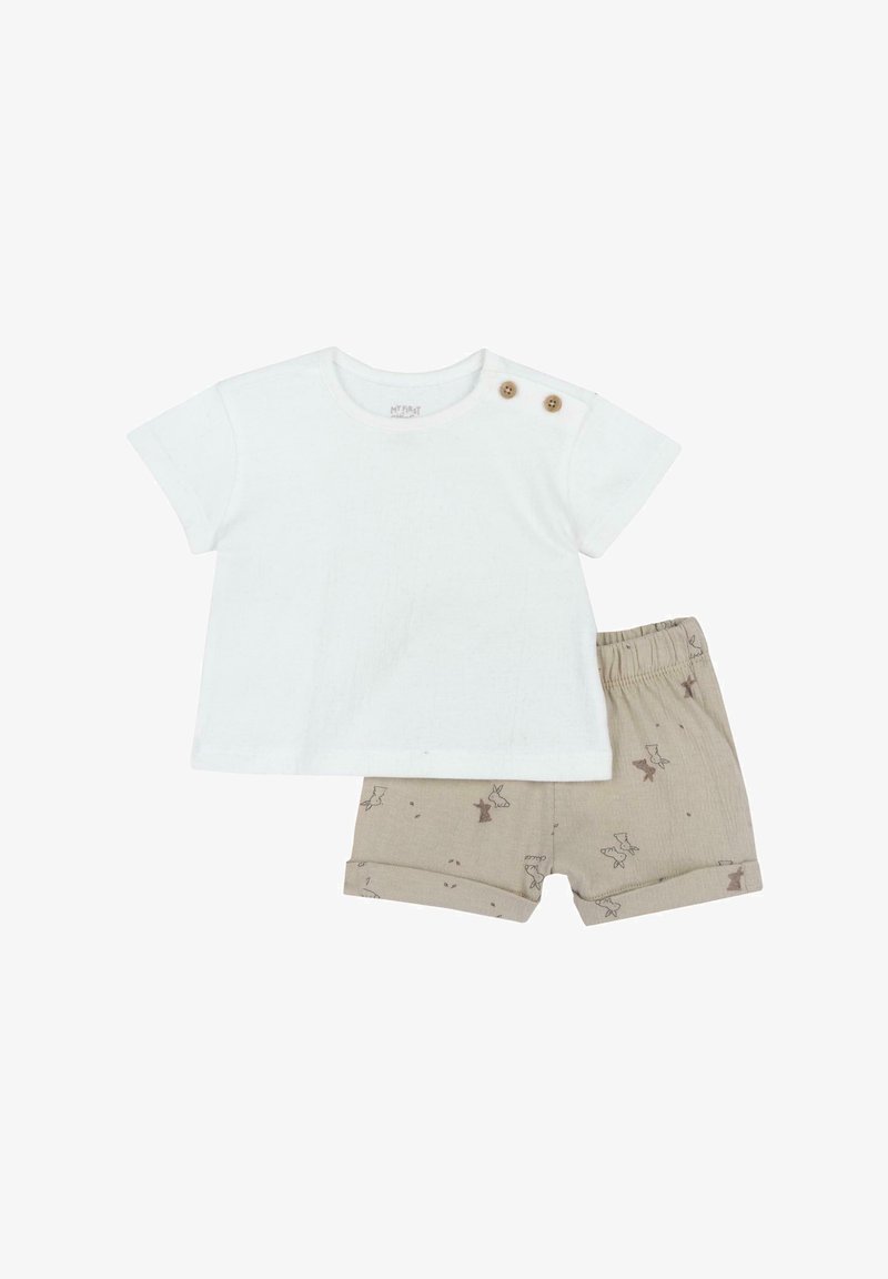 Witte katoenen t-shirt met twee houten knopen op de schouder; gecombineerd met beige shorts met een subtiele dierenprint en opgerolde cuffs.