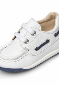 Scarpa in pelle bianca con accenti blu navy, punta tonda, due occhielli e lacci bianchi. Suola in gomma texturizzata con dettaglio di bordo cucito.