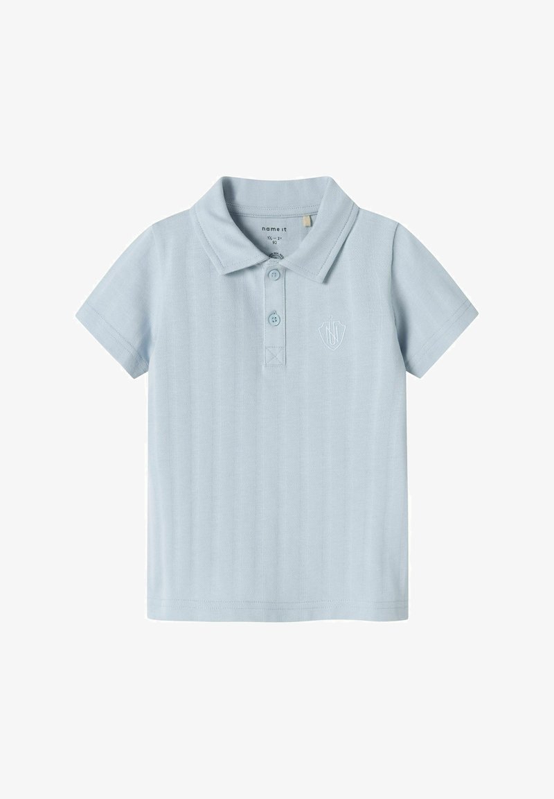Polo shirt bleu clair à manches courtes, en tissu texturé, avec un col, trois boutons, et un logo brodé sur la poitrine.