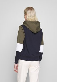 Sweatshirt com capuz apresentando um design em bloco de cores em azul marinho, verde-azeitona e branco; feito de um tecido macio com um corte descontraído.