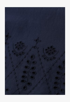 Marineblauwe stof met geborduurde bloemenuitgesneden patronen die een geometrisch ontwerp vormen langs het onderste gedeelte.