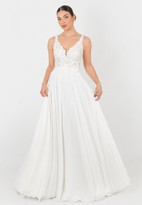 Abito bianco con corpino in pizzo e scollatura a V profonda. Gonna fluida con pieghe, design senza maniche e ricami floreali in vita.