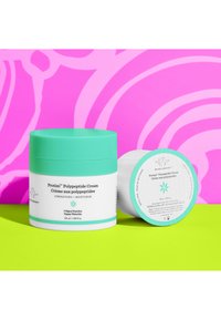 Moisturizing cream jar in white, with a teal lid and accents. Label features text in black and teal, displaying product details.