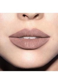 Matte nude lippenstift aangebracht op volle lippen met een zachte textuur, die de natuurlijke liplijnen accentueert en een subtiele glans op de omliggende huid geeft.