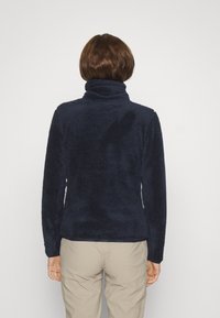 Felpa in pile blu navy con colletto alto e maniche lunghe, caratterizzata da un tessuto morbido e testurizzato e una vestibilità rilassata.