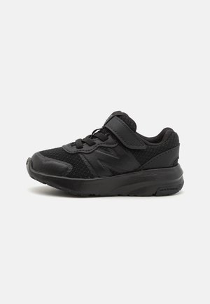 Black athletic shoe with mesh upper, rubber sole, lace-up and Velcro closure, featuring textured accents and a padded collar for comfort.