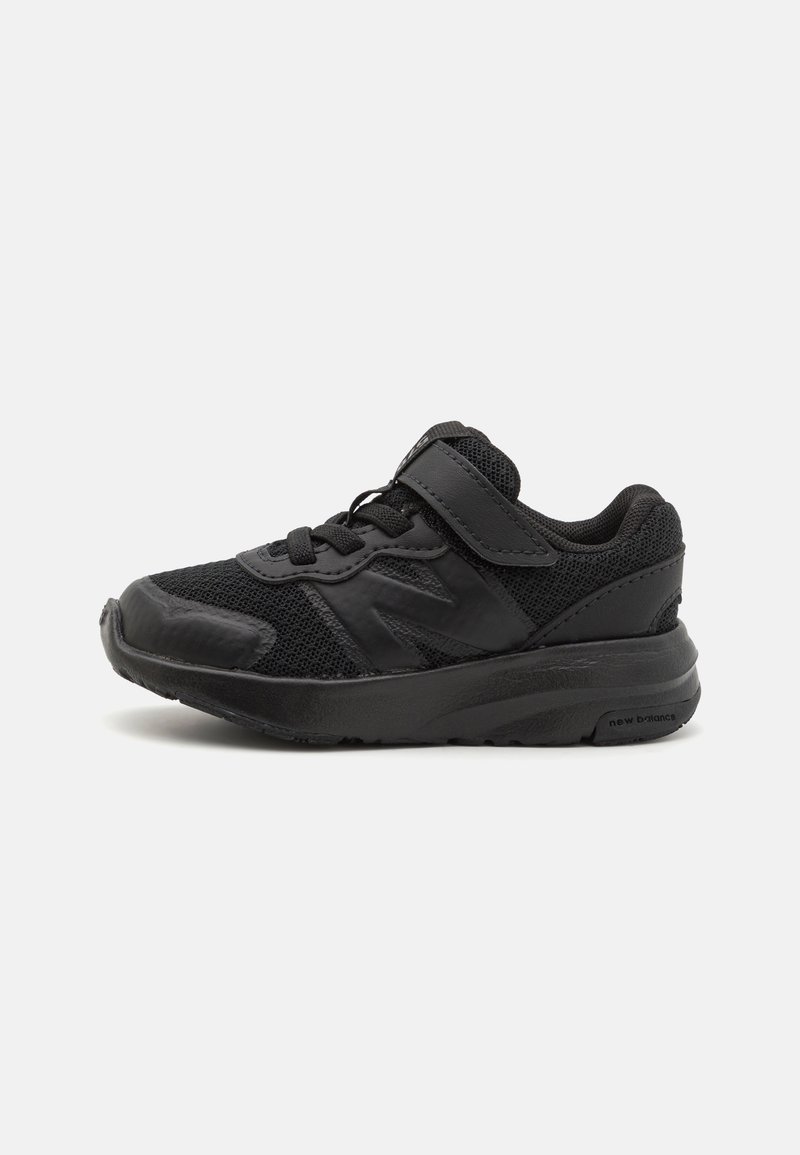 Chaussure de sport noire avec tige en mesh, semelle en caoutchouc, fermeture à lacets et Velcro, présentant des accents texturés et un col rembourré pour le confort.