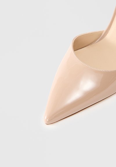Pumps cu toc înalt din piele patent nud, cu vârf ascuțit și design cu laturi deschise, evidențiind o textură netedă și strălucitoare.