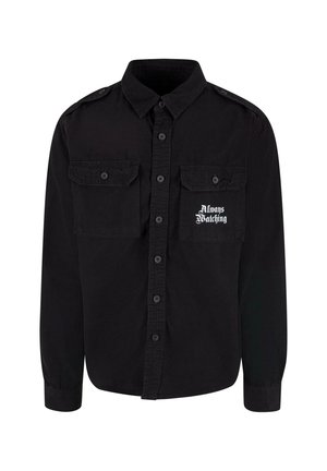 Chemise noire à manches longues avec un devant à boutons, deux poches poitrine, et le texte imprimé "Toujours à l'affût" en blanc. Fabriquée en tissu texturé.