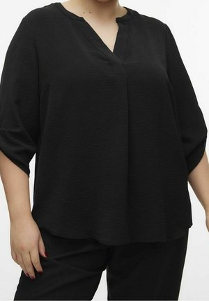 Blusa negra de corte holgado con tejido texturizado, escote en V y mangas ligeramente recortadas. Diseñada para mayor comodidad y libertad de movimiento.