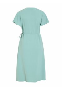 Robe mi-longue vert clair avec manches courtes flottantes et ceinture nouée à la taille, vue de dos sur un fond blanc uni.