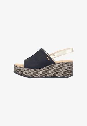 Black wedge sandal with woven platform sole, beige cushioned footbed, open toe, and light gold adjustable ankle strap.