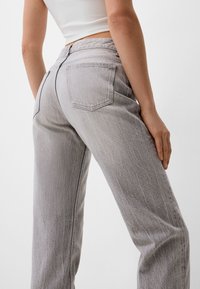 Jeans wide-leg in denim grigio con vita alta, dotati di due tasche posteriori e una leggera texture. Il tessuto presenta un finitura leggermente lavata.