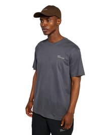 Mężczyzna w ciemnoszarej koszulce i brązowej czapce z daszkiem, oba z nadrukiem "HALO" i numerami, stoi na białym tle.