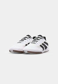 Scarpe sportive bianche con accenti neri e lacci, caratterizzate da una parte superiore texture, area della punta perforata e suola in gomma naturale.