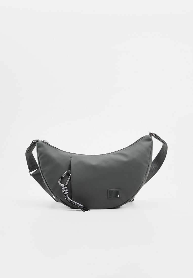 Bolso bandolera gris de nailon con forma curva, correa ajustable, cierre con cremallera y un cordón tejido como acento. Presenta una pequeña etiqueta en la parte frontal.