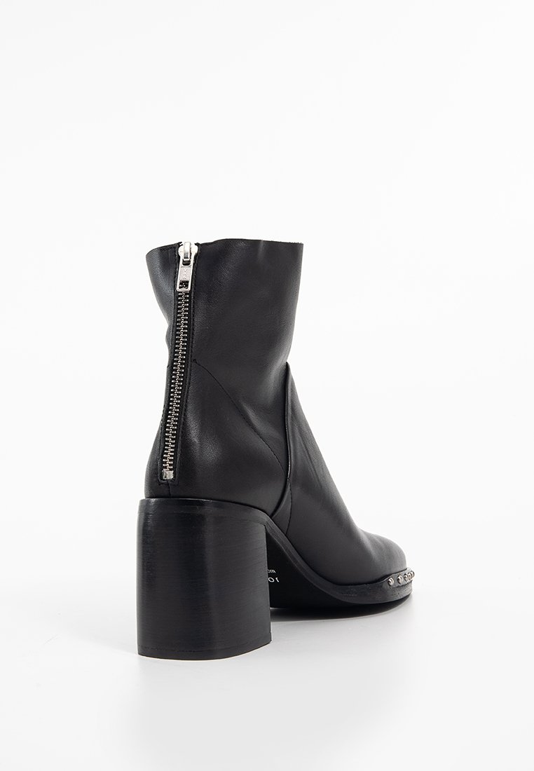 Schwarze Leder-Stiefelette mit klobigem Absatz, seitlichem Reißverschluss, glatter Textur und silbernem Hardware-Akzent entlang der Sohle.