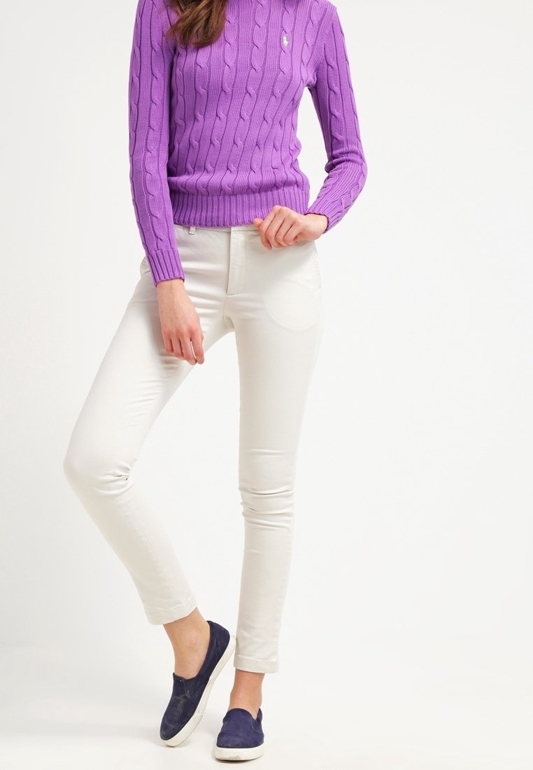 Lila kabelstickad tröja, vita slim fit-jeans och marinblå slip-on-skor. Anmärkningsvärda detaljer inkluderar ribbade muddar och en diskret logotyp på tröjan.