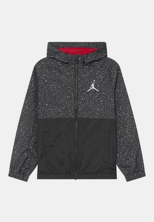 Giacca con cappuccio a pois neri e grigi con cerniera frontale, due tasche e logo Jumpman bianco sul petto, fodera interna rossa visibile all'interno del cappuccio.