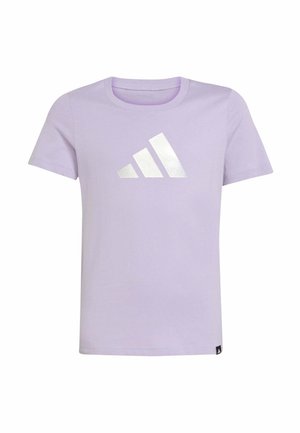 Joven con cabello negro vistiendo una camiseta Adidas de color púrpura claro y pantalones púrpura oscuro, de pie con las manos detrás de la espalda.
