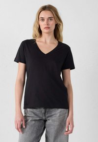 T-shirt nera a maniche corte con scollatura a V, realizzata in tessuto morbido, con una vestibilità comoda e un piccolo logo ricamato in basso a sinistra.