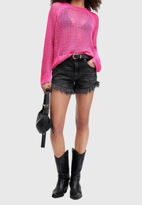 Różowy dzianinowy, oversize'owy sweter, czarne postrzępione szorty dżinsowe, czarne kowbojskie botki oraz okrąła czarna torebka. Skupienie na fakturze i intensywnych kolorach.