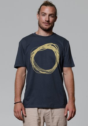 Navy blue cotton t-shirt featuring a large, textured circular design in light gold. Short sleeves and a round neckline.
