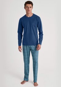 Heren loungekleding met een effen blauwe lange mouw shirt met een borstzak en gestreepte blauwe pyjamabroek met een geometrisch ontwerp.