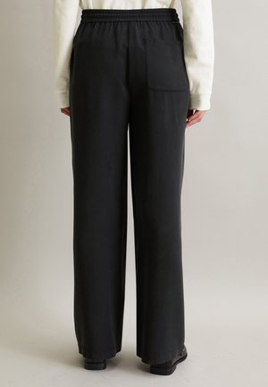 Zwarte wijde broek met een elastische tailleband en een enkele achterzak. De stof lijkt glad met een matte afwerking.