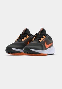 Černé běžecké boty s oranžovými akcenty. Síťovina na svršku, gumová podrážka, polstrovaný límec a tkaničky. Ikonický swoosh Nike na boku.