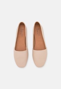 Chaussures plates beige clair en cuir lisse, avec un bout arrondi et un design simple. L'intérieur est doté d'une semelle intérieure marron douce.