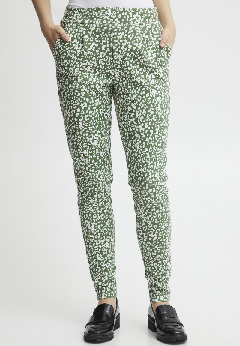Groene, gestreepte broek met wit luipaardmotief; heeft zijzakken en een aansluitend ontwerp. Gepaard met zwarte instappers.