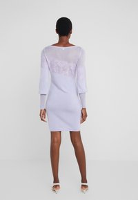 Abito a maglia lavanda con dettagli in pizzo trasparente sulle maniche e sul retro, forma aderente, polsini a coste e lunghezza fino a metà coscia.