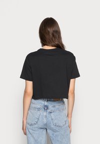 Avskuren svart bomulls-t-shirt med korta ärmar och rund halsringning, kombinerad med högmidjade ljusblå denimjeans med bakfickor.