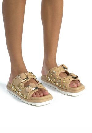 Sandales à plateforme nudes avec des accents cloutés, deux brides ajustables, une semelle texturée et un design à bout rond. Convient pour un port décontracté.