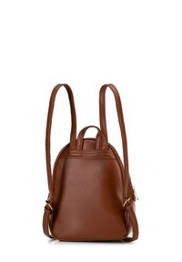 Mochila de cuero sintético marrón con correas dobles, forma redondeada y pequeño asa en la parte superior. Presenta accesorios en tono dorado y un detalle minimalista.